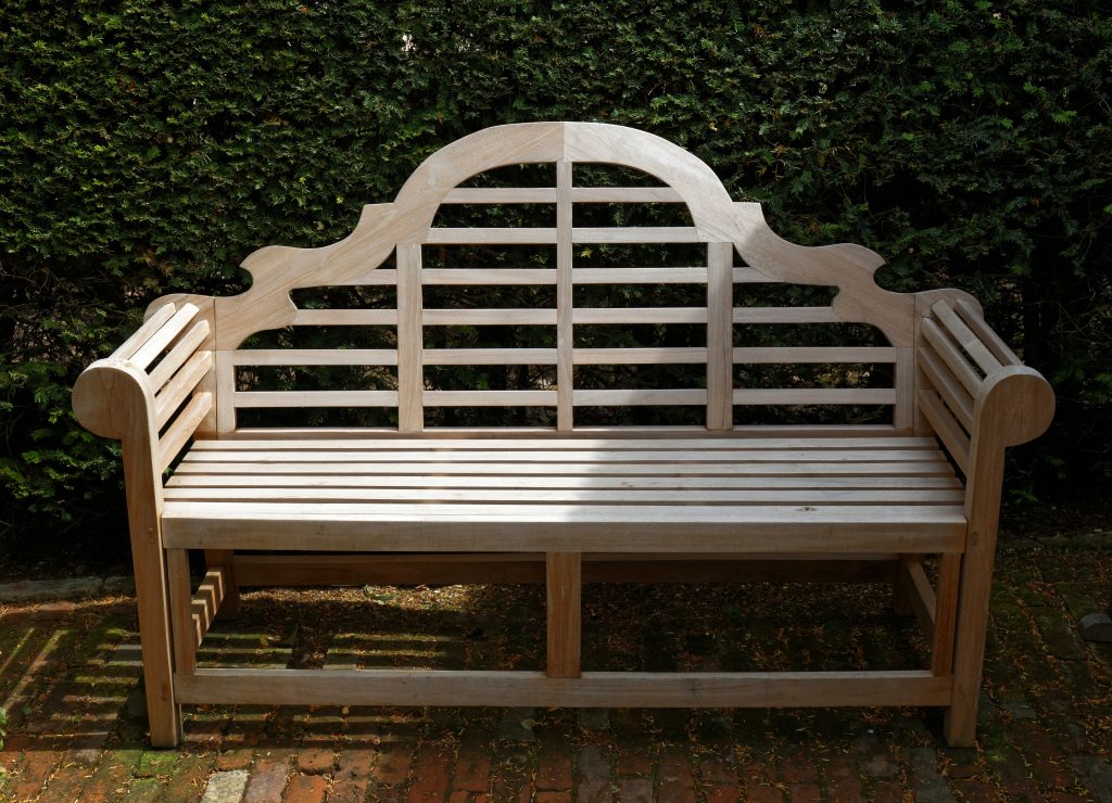 Banc en bois clair installe dans un coin de jardin pour un espace detente exterieur