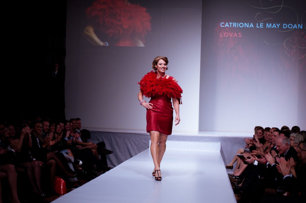Robe longue rouge corail portée lors d'un défilé, illustrant les couleurs vives de l'été 2026