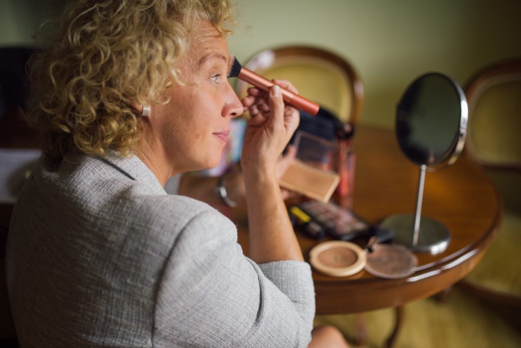 Femme appliquant son maquillage devant un miroir en ete