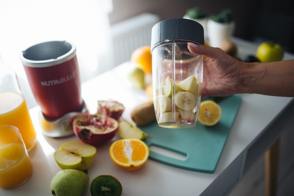 Préparation d'un smoothie maison avec des fruits frais dans une cuisine lumineuse