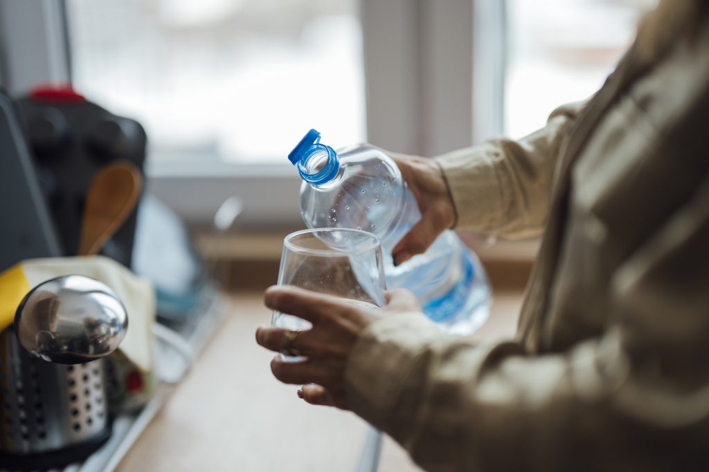 Verre d'eau que l'on remplit, geste d'hydratation quotidien