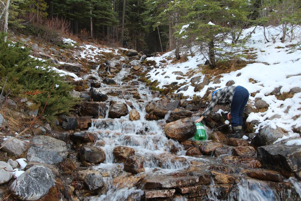 Femme remplissant sa gourde d'eau en pleine nature