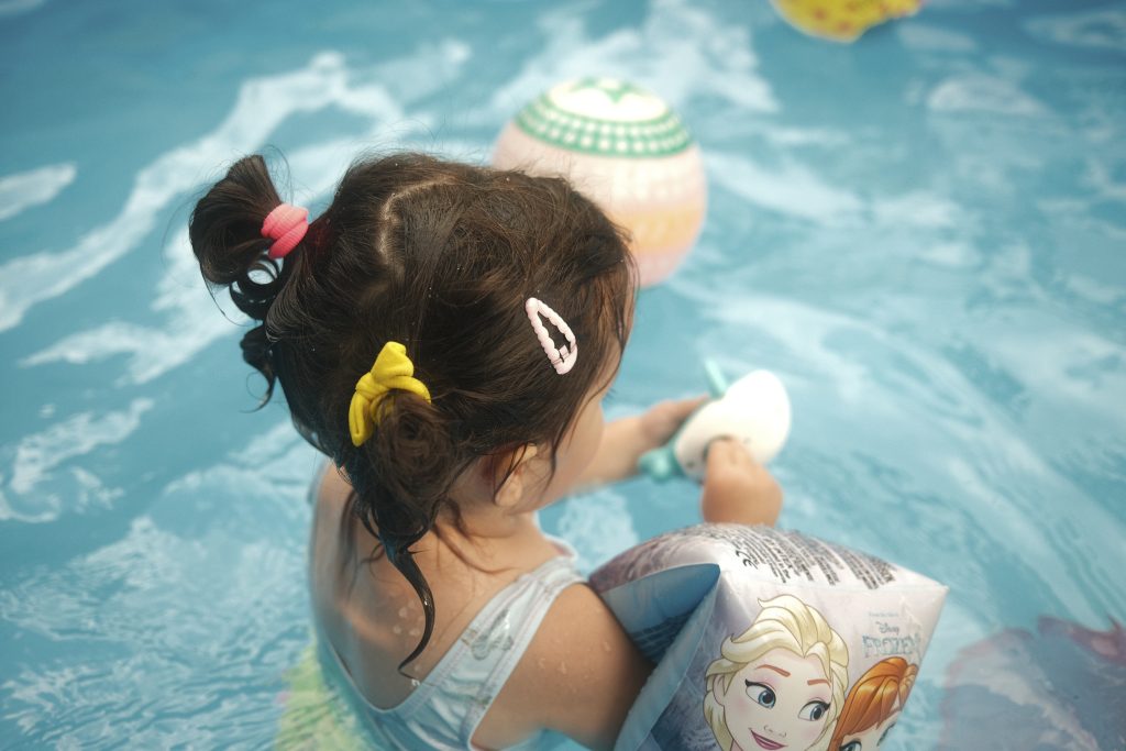 Bébé jouant avec des jouets gonflables colorés dans une piscine ensoleillée