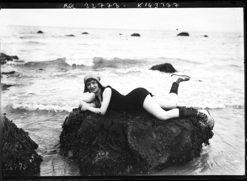Femme posant en maillot de bain allongee sur un rocher au bord de la mer