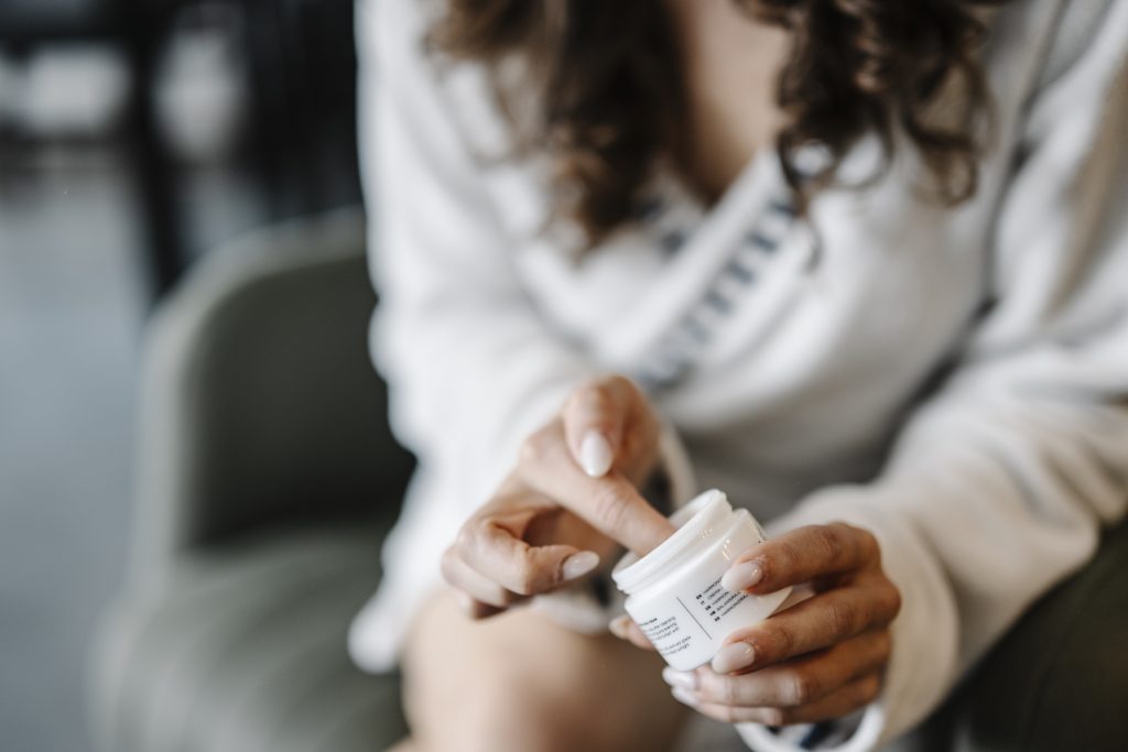 Femme appliquant une crème hydratante sur son visage pour resserrer les pores dilatés
